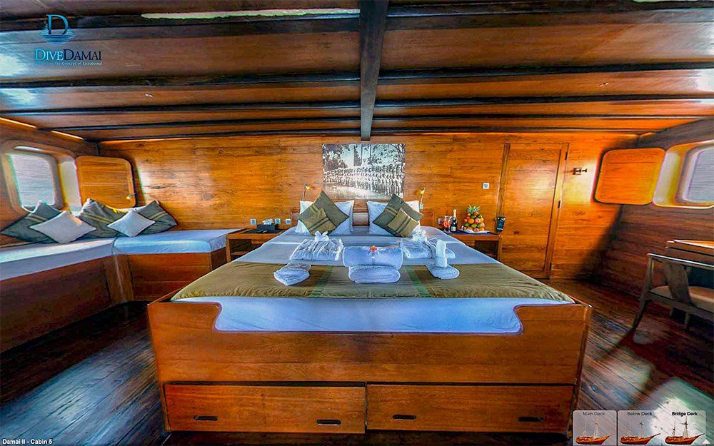 Wooden cabin interior of a boat, featuring a large bed and seating area.