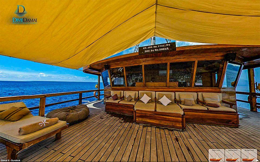 Wooden deck with seating and ocean view under a yellow canopy.