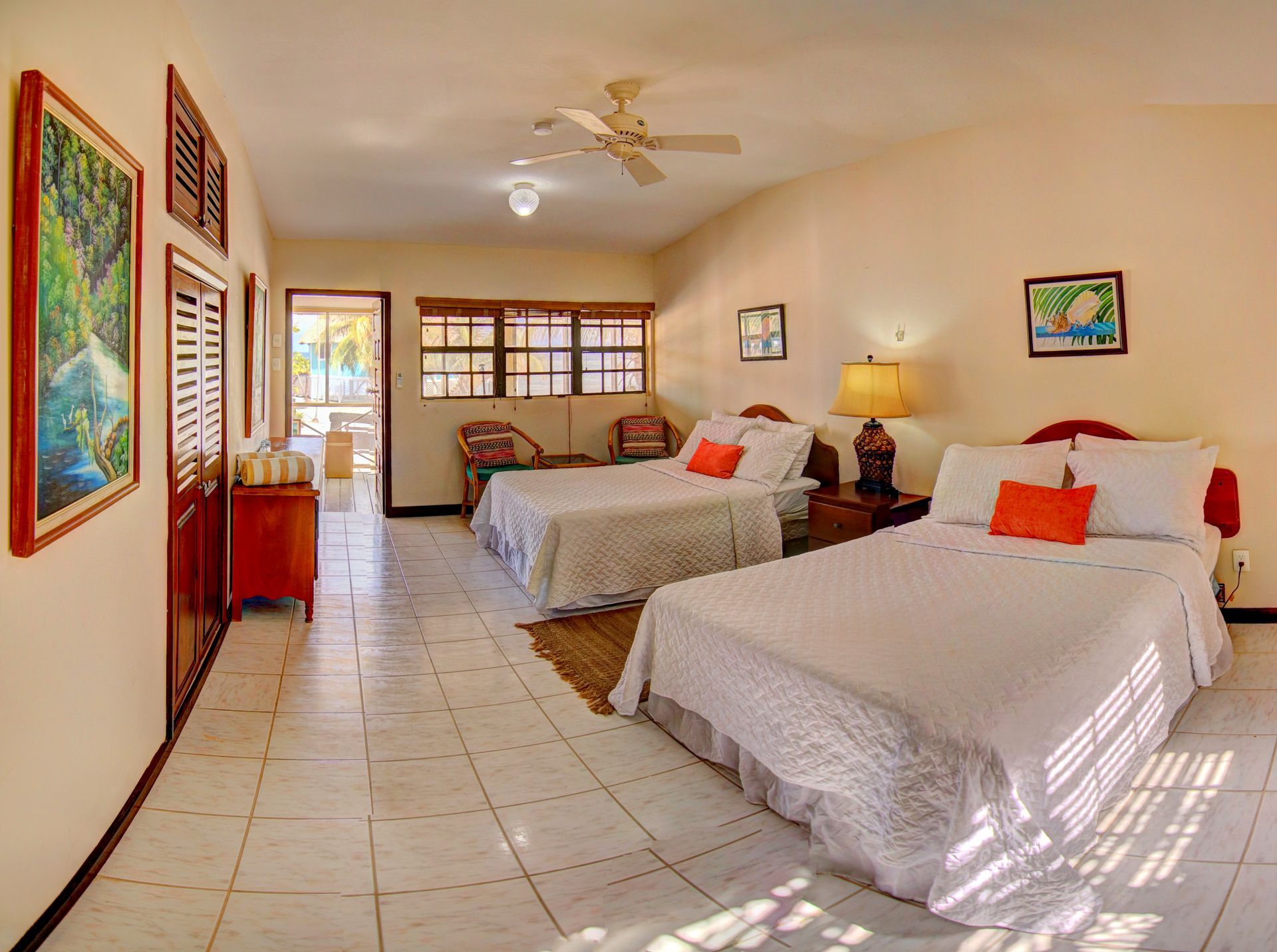 Bright bedroom with two beds, art, and an open door to a patio.