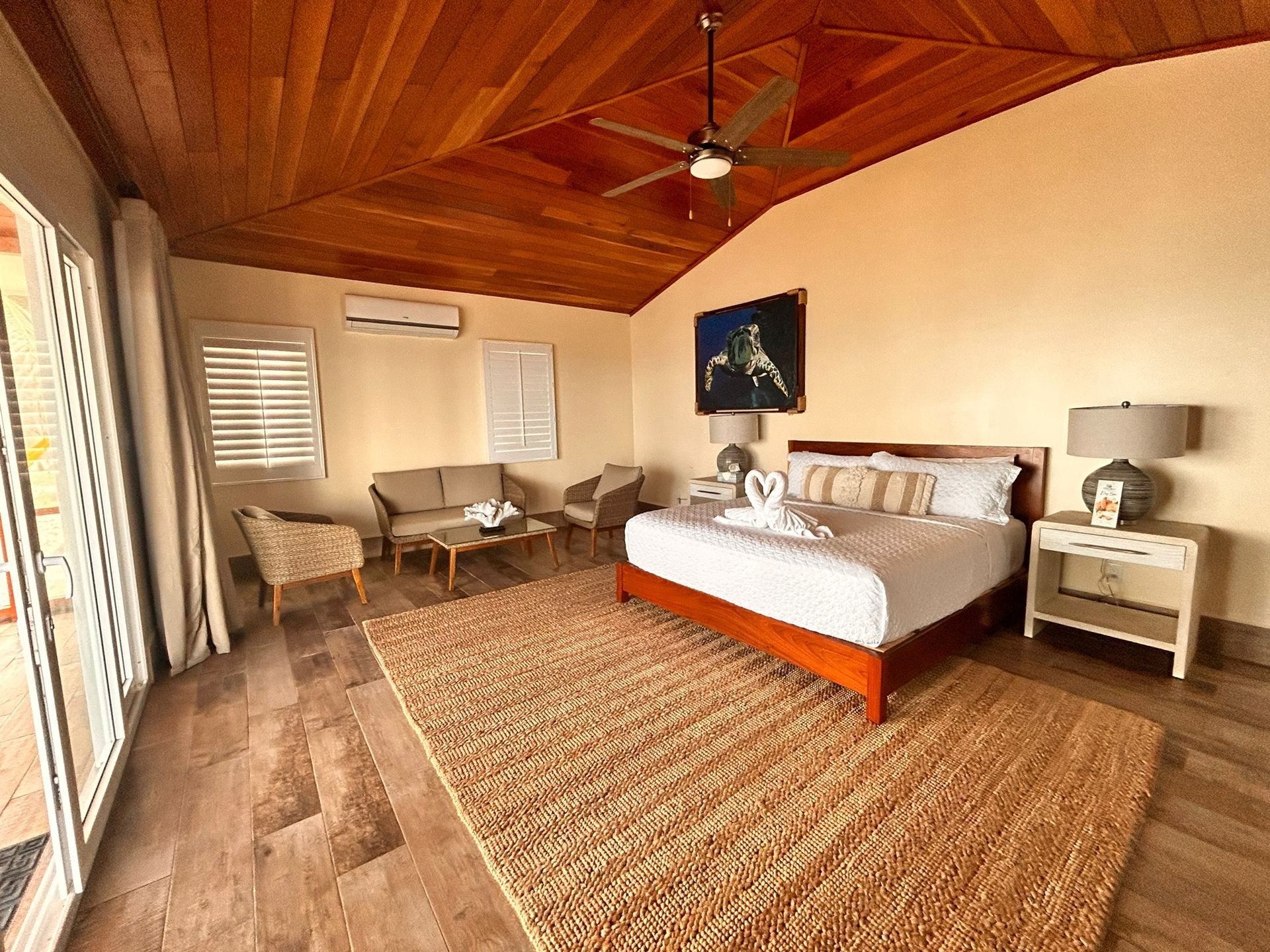 Bedroom with wooden ceiling, rug, bed, sofa, and sliding door to a patio.