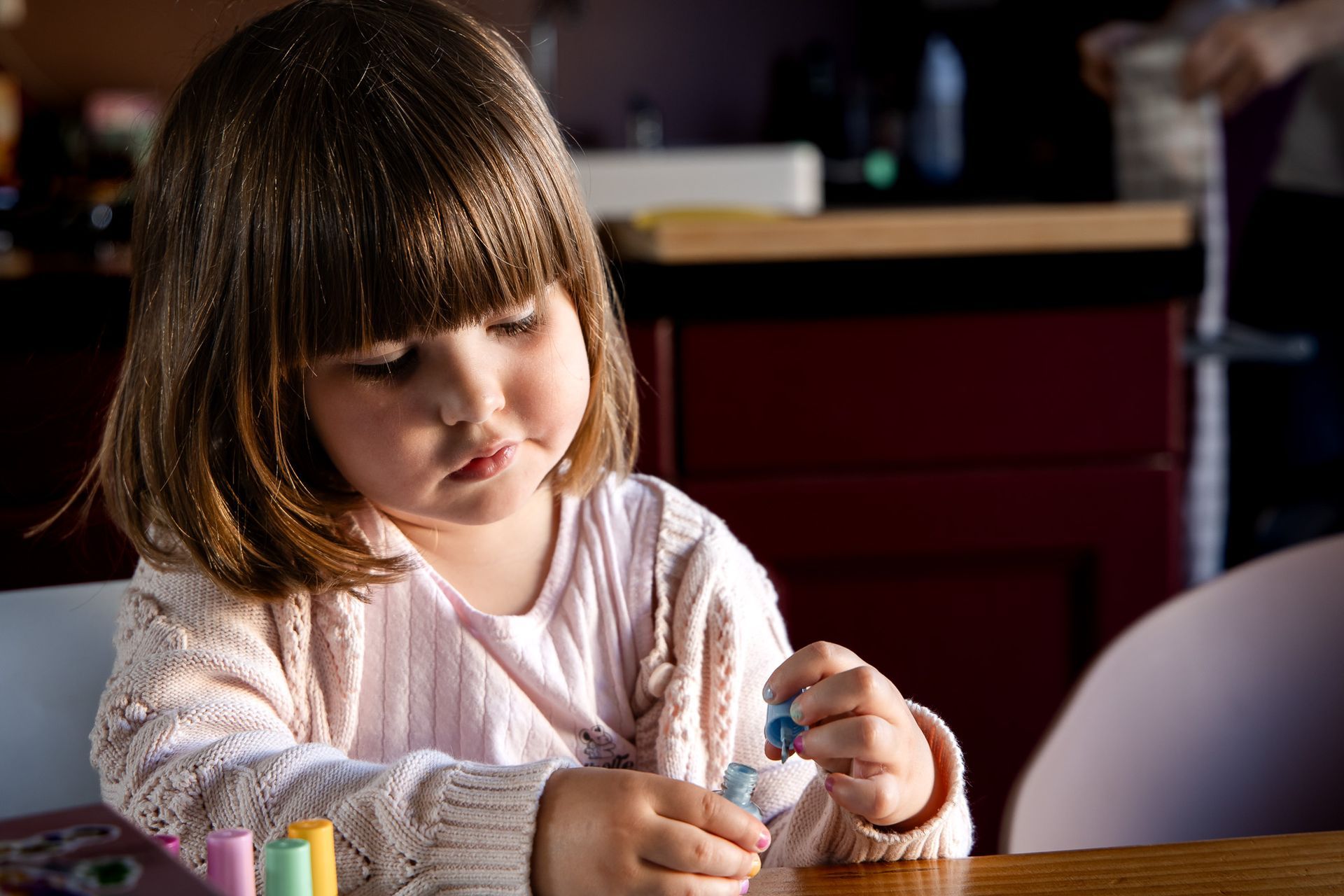 Peuter speelt geconcentreerd met nagellak aan tafel tijdens een Day in the Life reportage