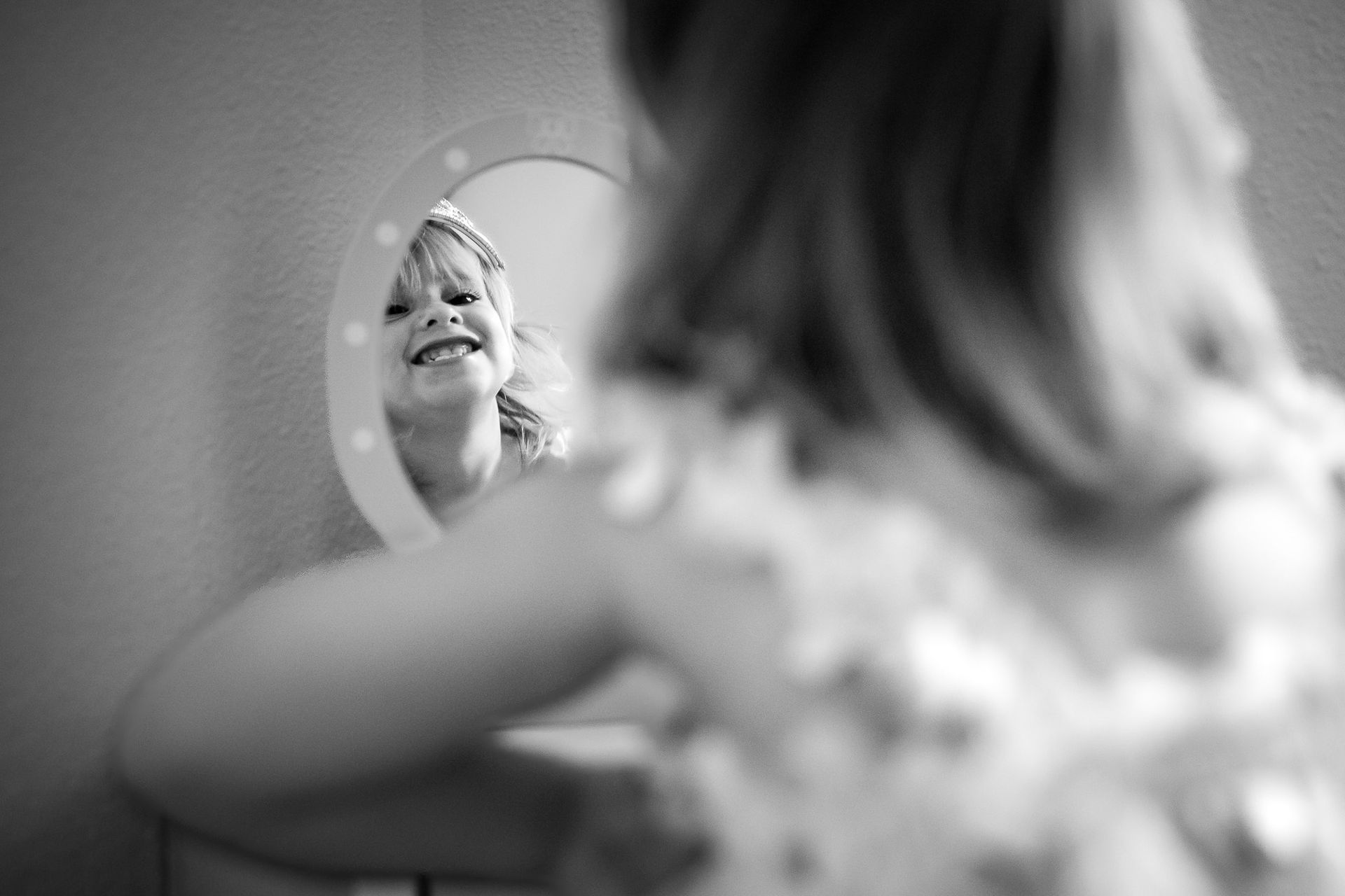 Kind kijkt lachend in een spiegel tijdens een documentaire Day in the Life fotosessie thuis