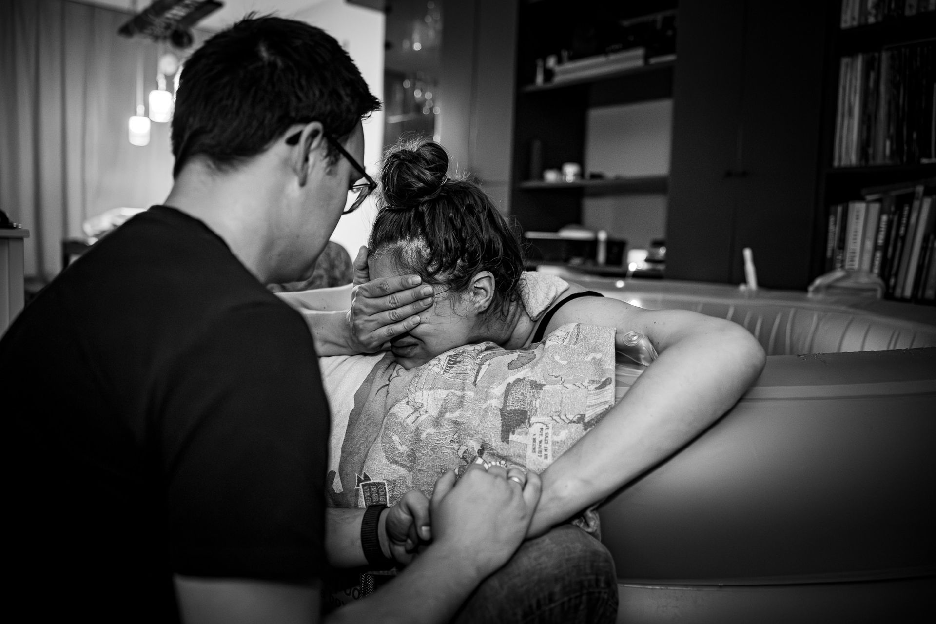 Partner ondersteunt vrouw tijdens de bevalling terwijl zij in het bevalbad zit.