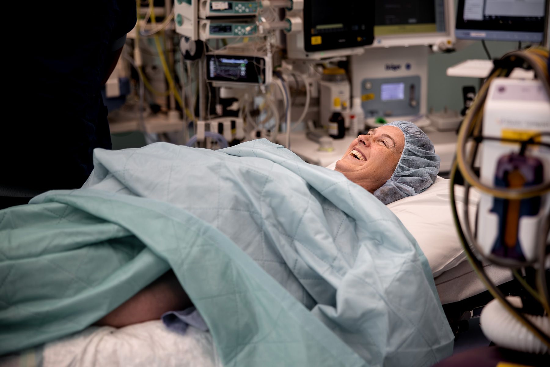 Vrouw ligt lachend op de operatietafel vlak voor een geplande keizersnede