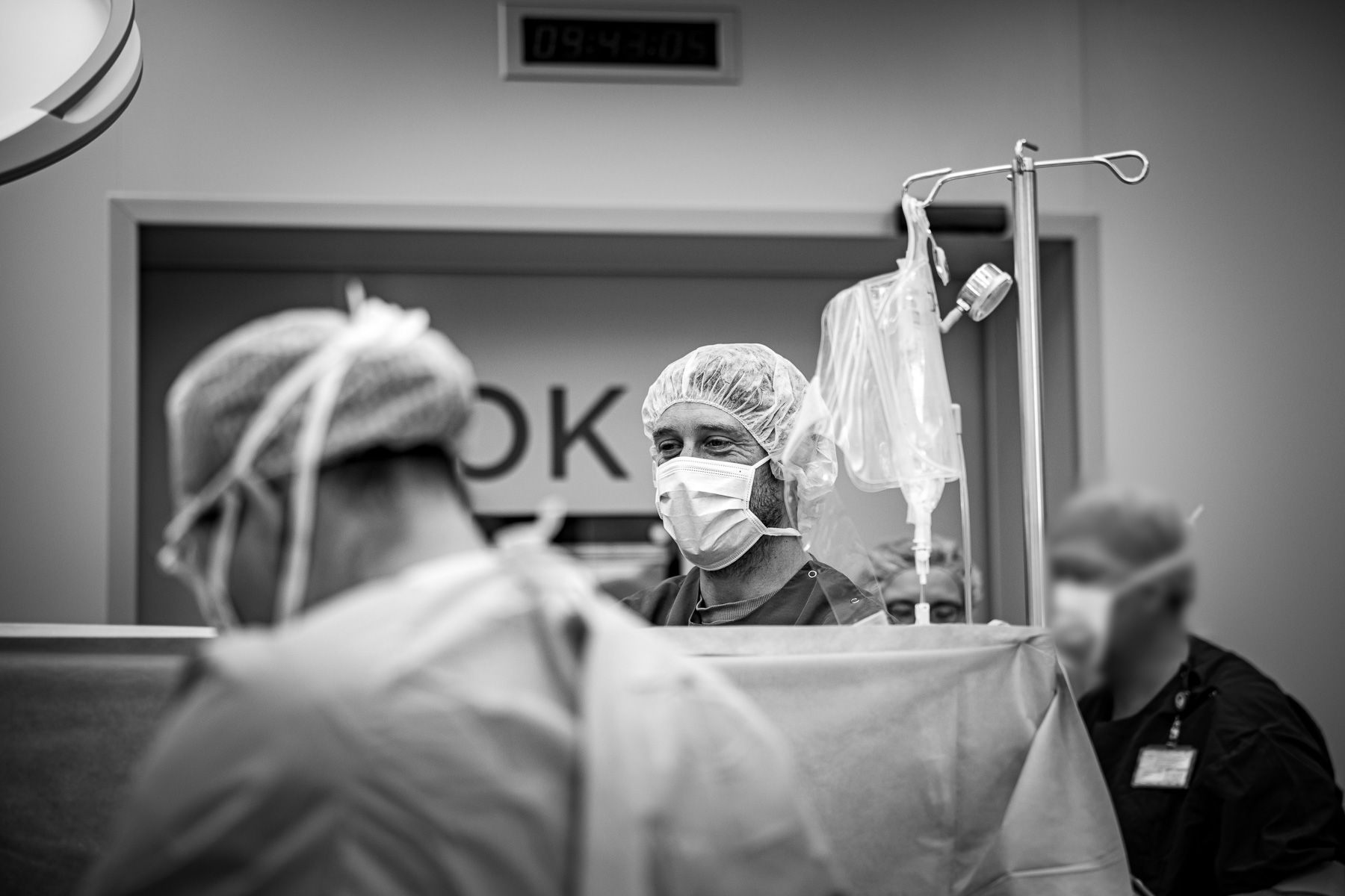 Vader kijkt mee bij de geboorte van zijn baby tijdens een keizersnede in de operatiekamer.