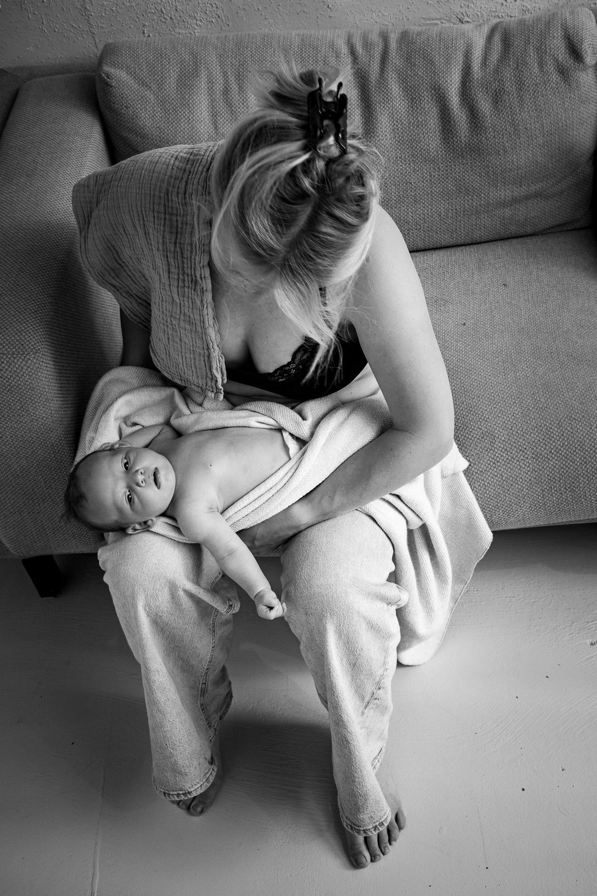 Moeder met pasgeboren baby op schoot thuis, vlak na borstvoeding