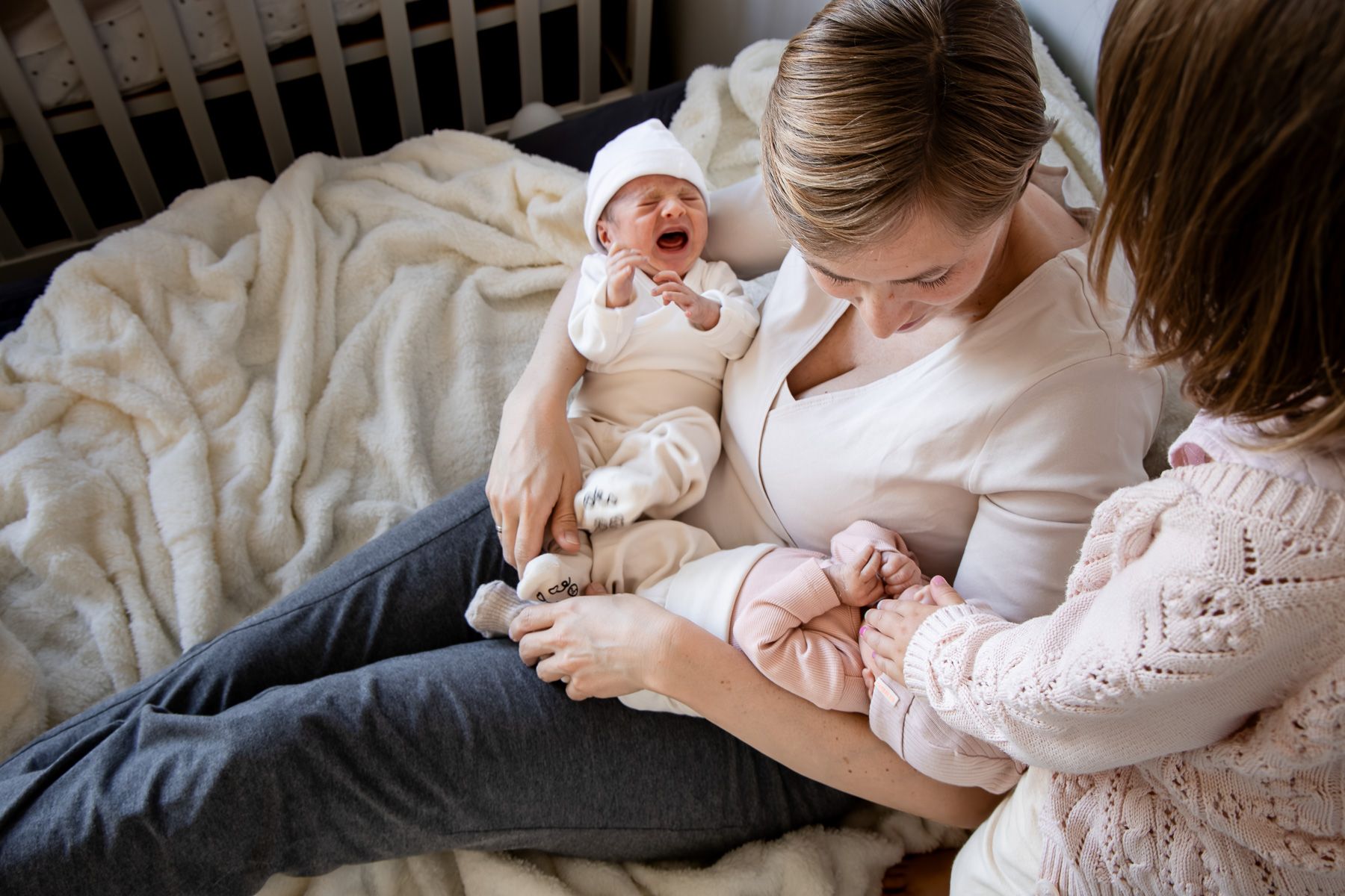 Moeder met pasgeboren tweeling en gezinsmoment tijdens newbornreportage aan huis