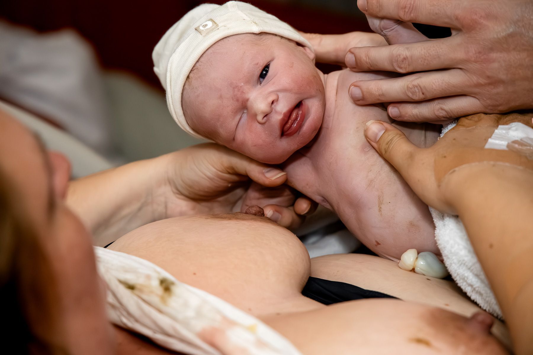 Pasgeboren baby direct na de geboorte, baby geeft knipoog