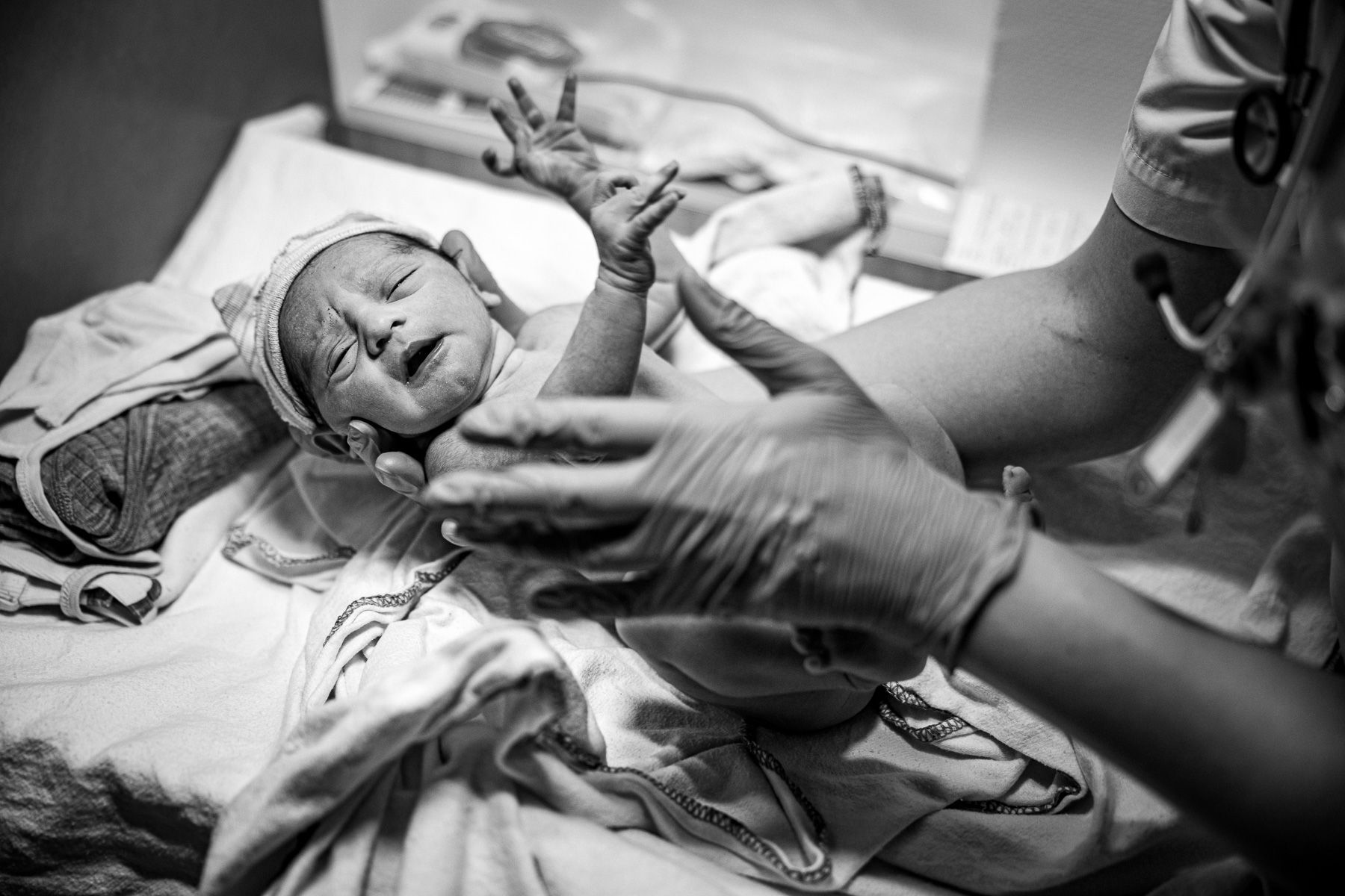 Pasgeboren baby direct na de geboorte terwijl verpleegkundige de baby verzorgt en controleert.