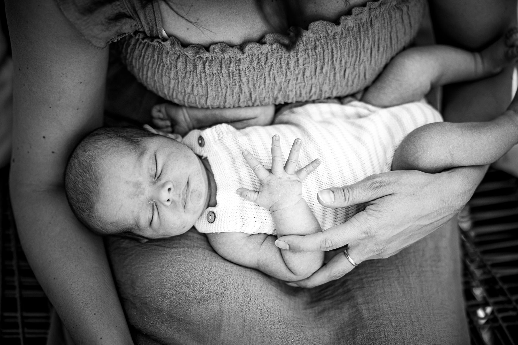 Pasgeboren baby in de armen van moeder tijdens newbornfotografie