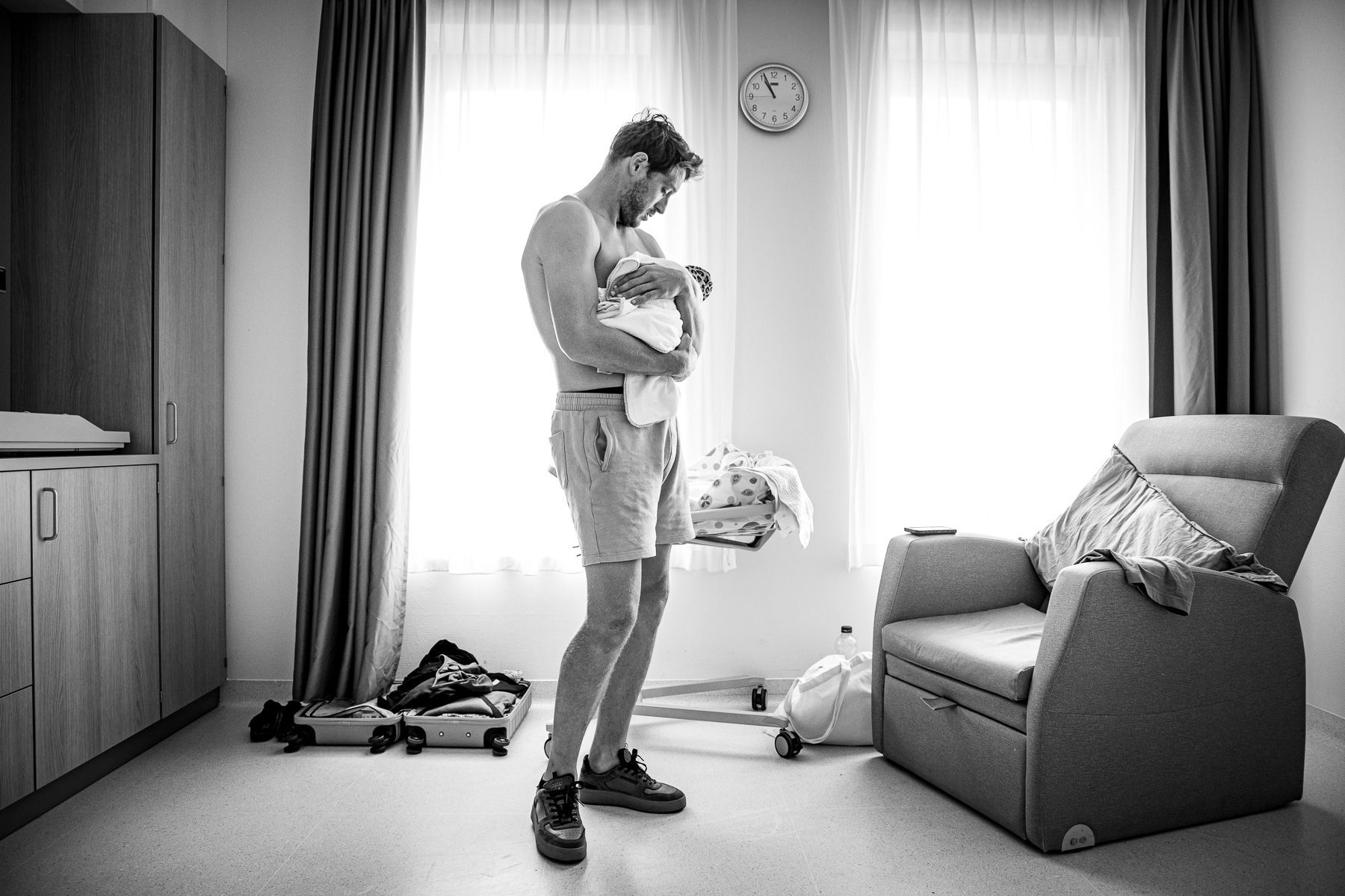 Vader houdt zijn pasgeboren baby vast in de ziekenhuiskamer na de geboorte.