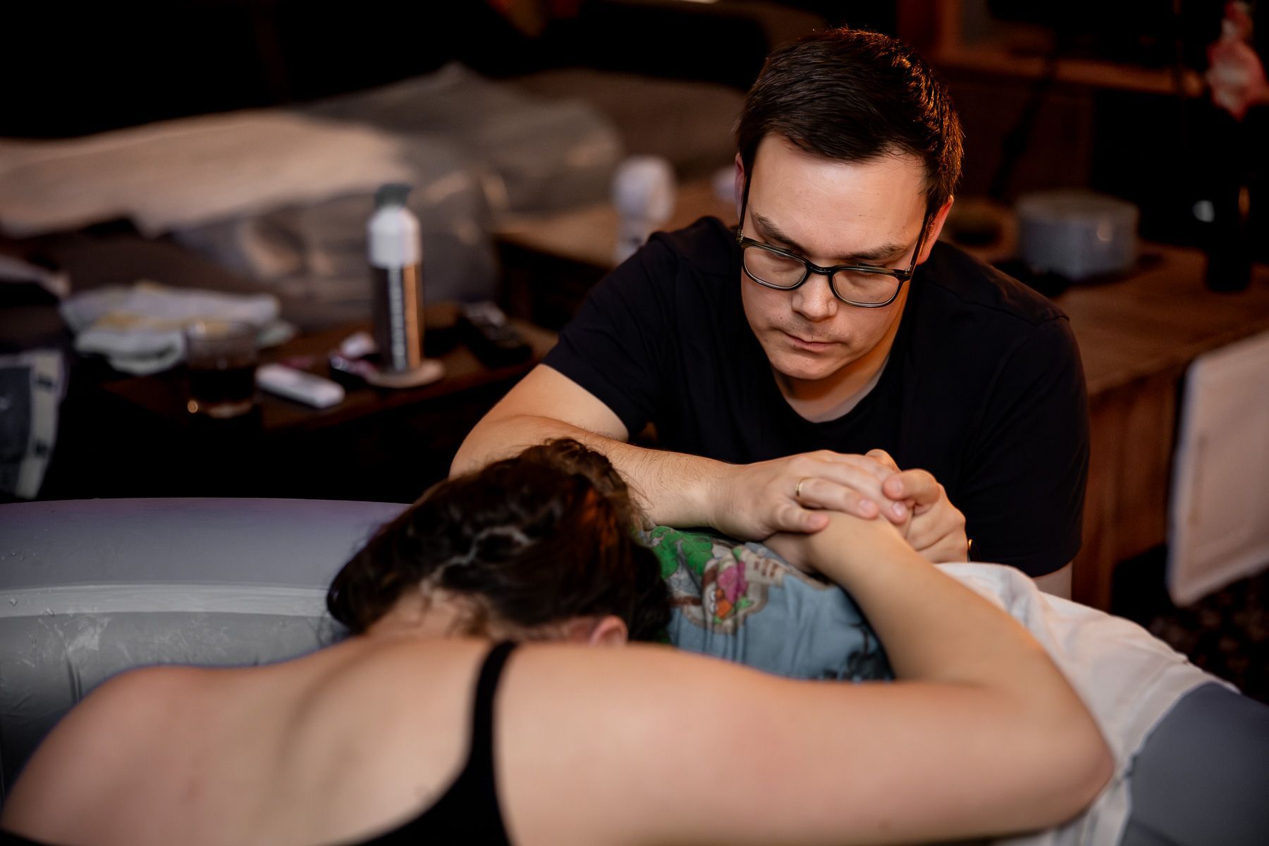 Vader ondersteunt zijn partner tijdens de bevalling terwijl zij in het bevalbad zit.