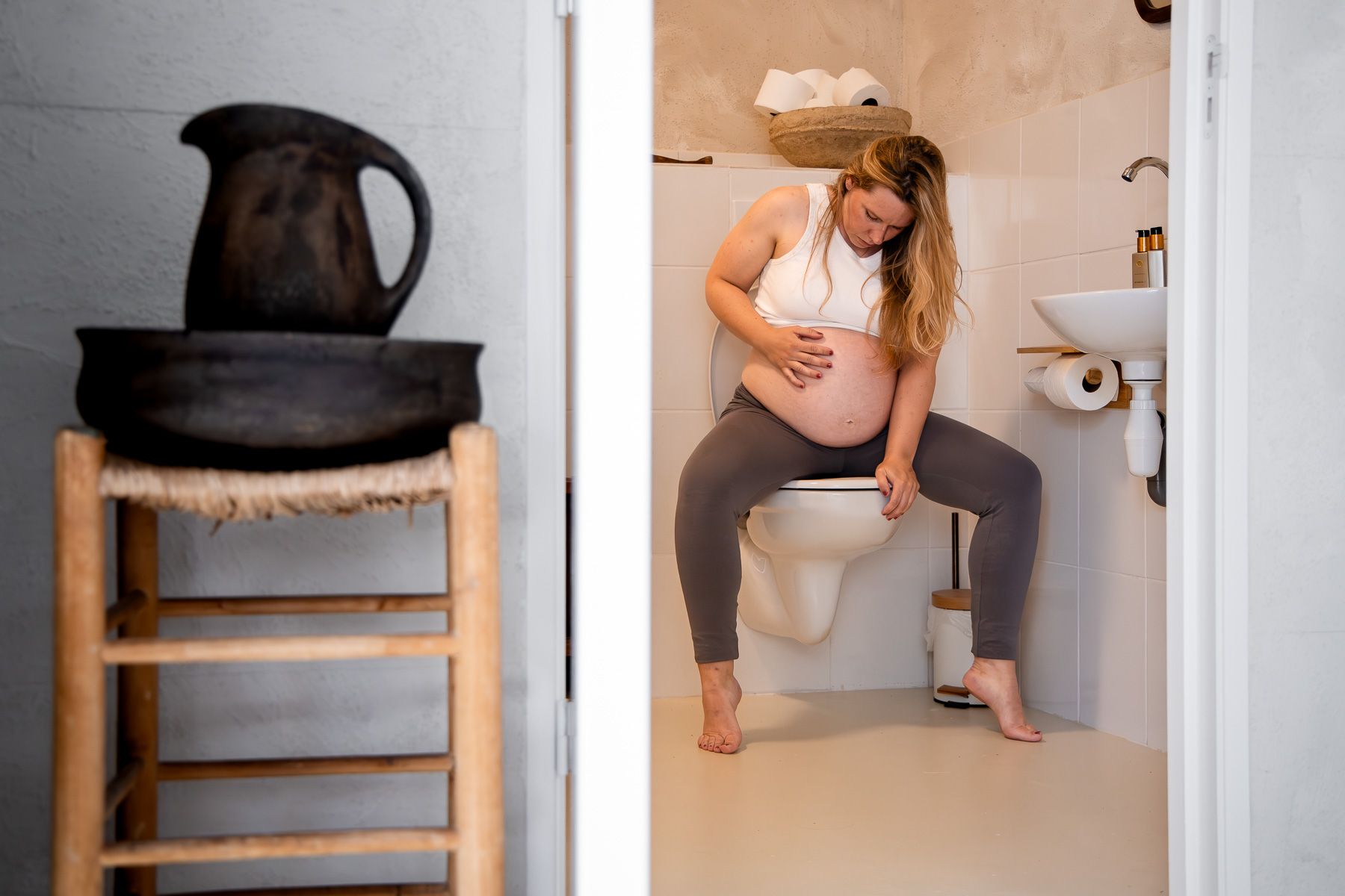Zwangere vrouw zit op het toilet tijdens de bevalling in een badkamer