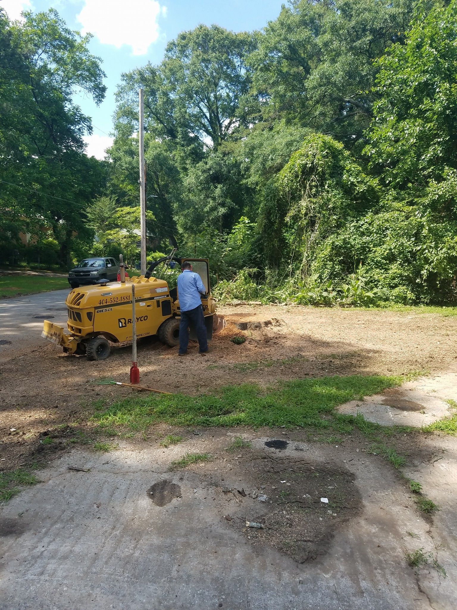 A man is standing next to a stump grinder in a yard.