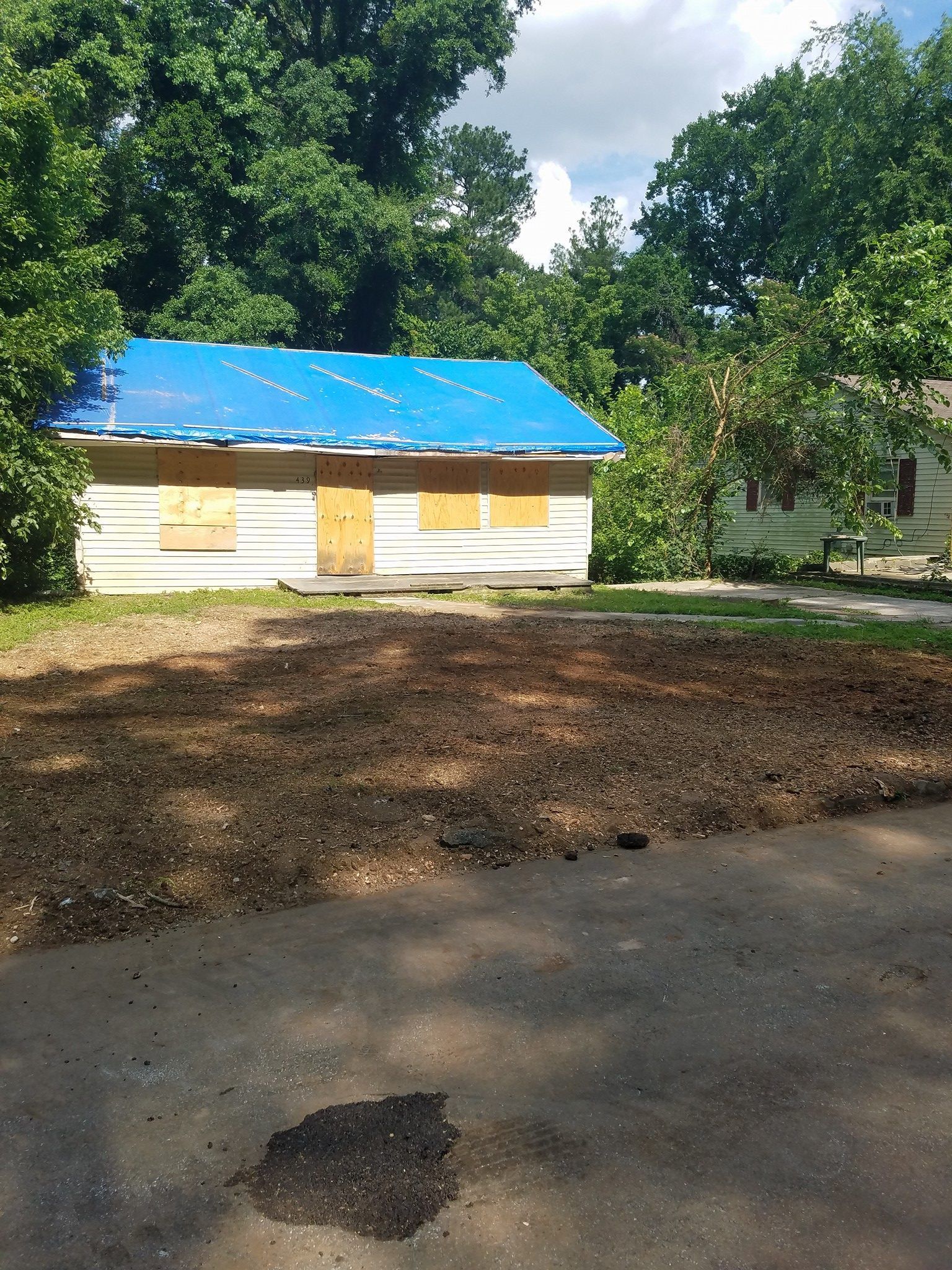 A house with a blue roof is sitting in the middle of a dirt field.
