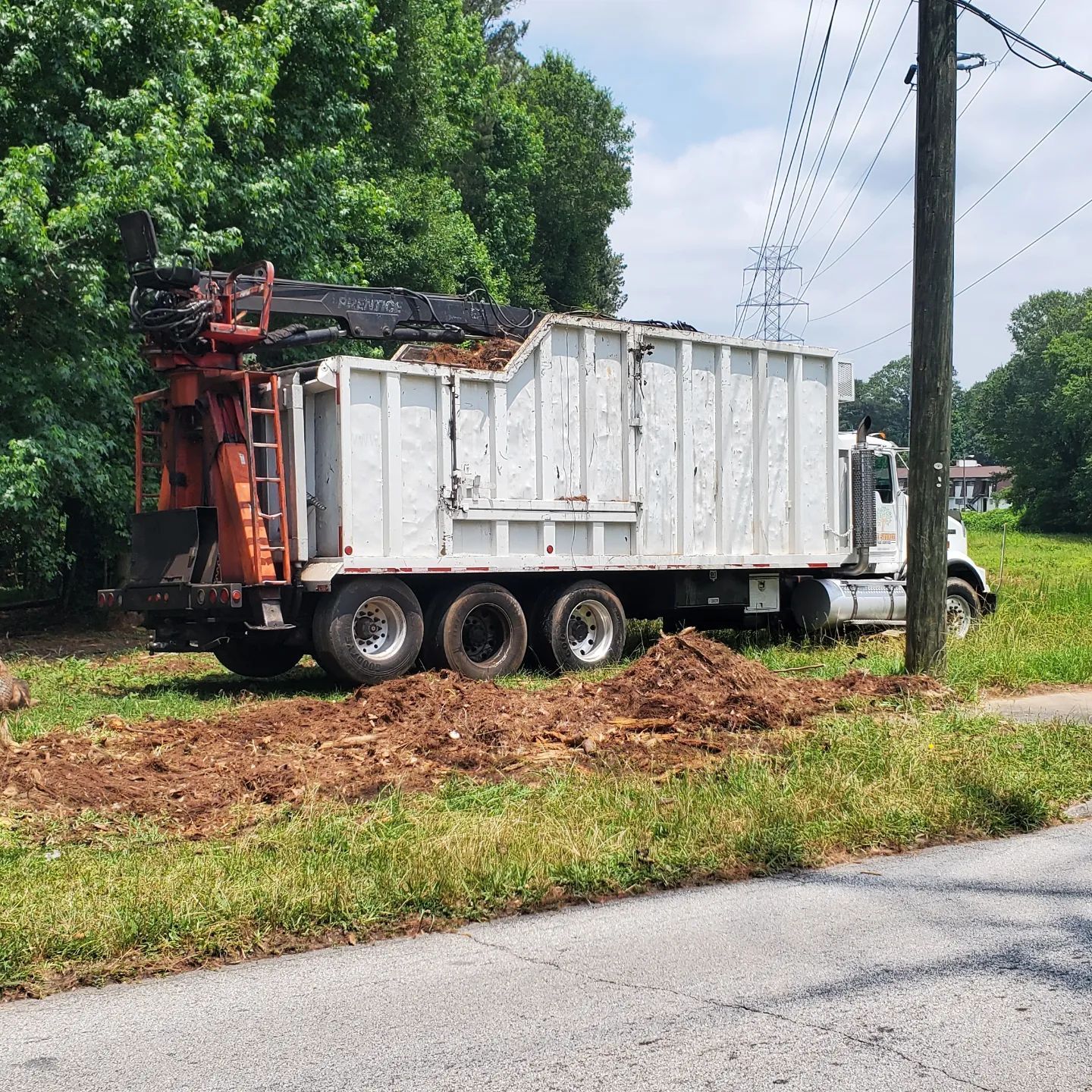 A white dump truck is parked on the side of the road
