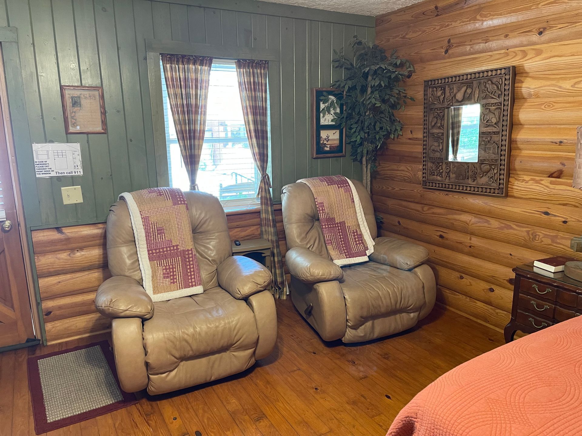 Two beige recliners with blankets in a cabin-style room with wood paneling and a window.