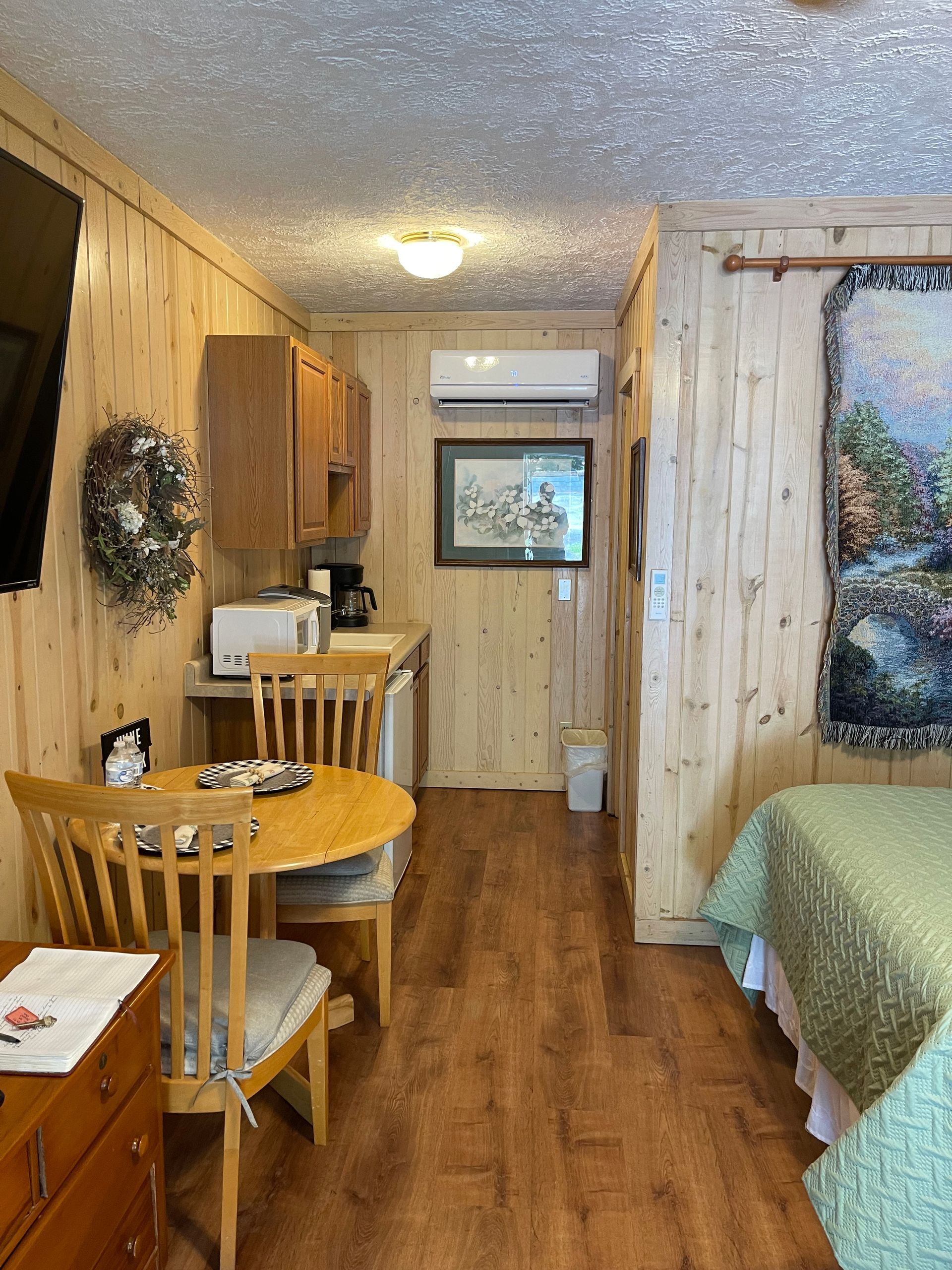 Small cabin interior with wood paneling, two beds, kitchenette, and a table.