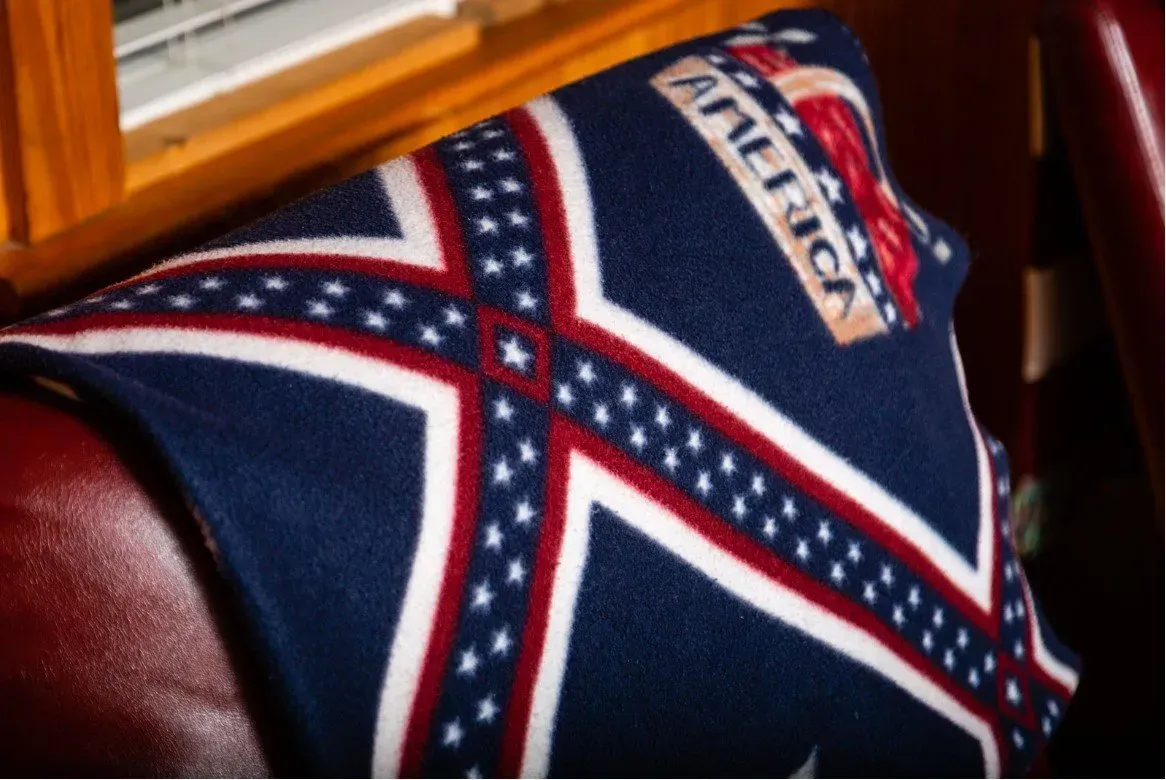 Blanket with the Confederate battle flag design draped over a red leather seat.