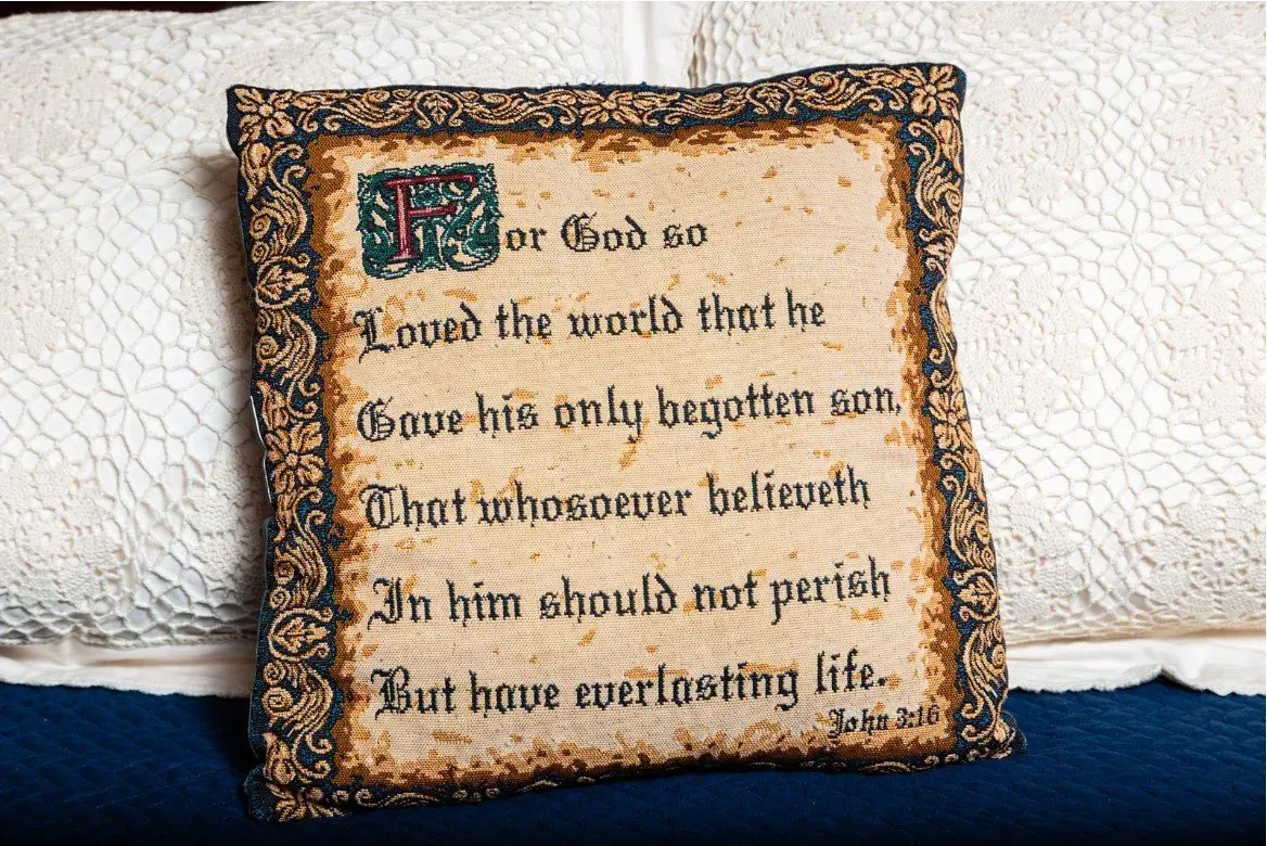 Text on a framed cloth with the Bible verse John 3:16.