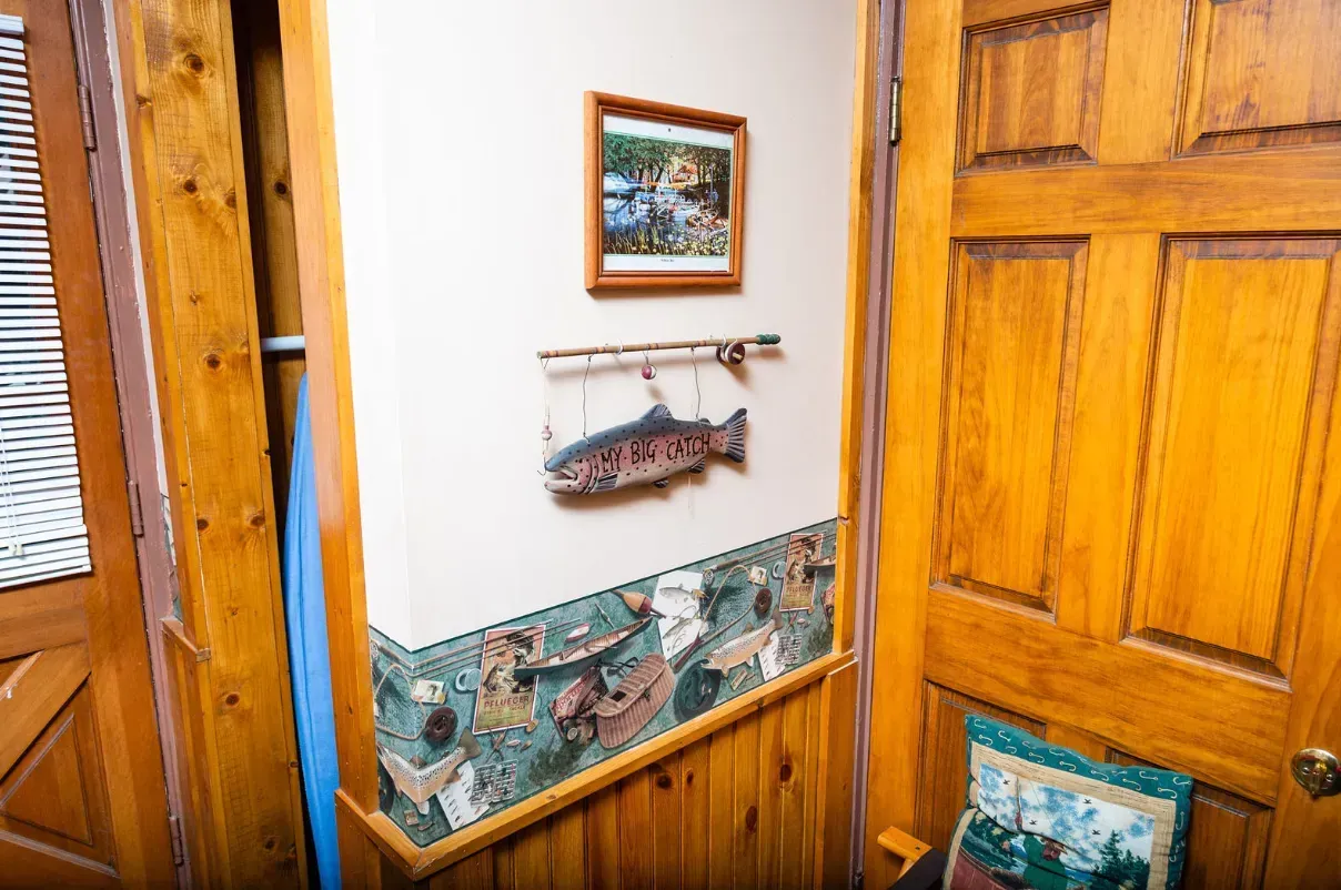 Entryway with wooden door and paneling. A fish decorates the wall above a border with aquatic illustrations.