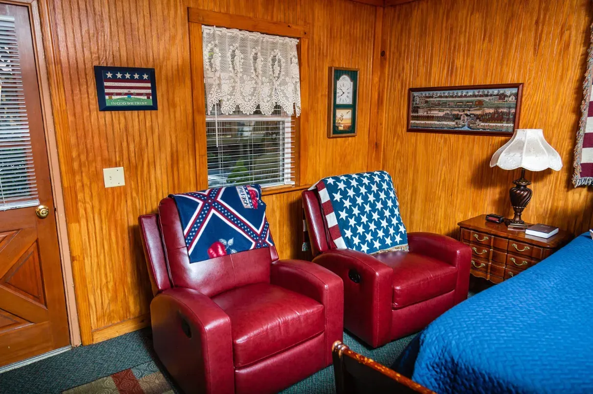 Two red recliners with blue and white blankets, in a wood-paneled room.