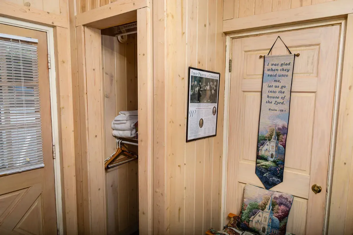 Hallway with wooden paneling, closet, door, and decorative wall hangings.