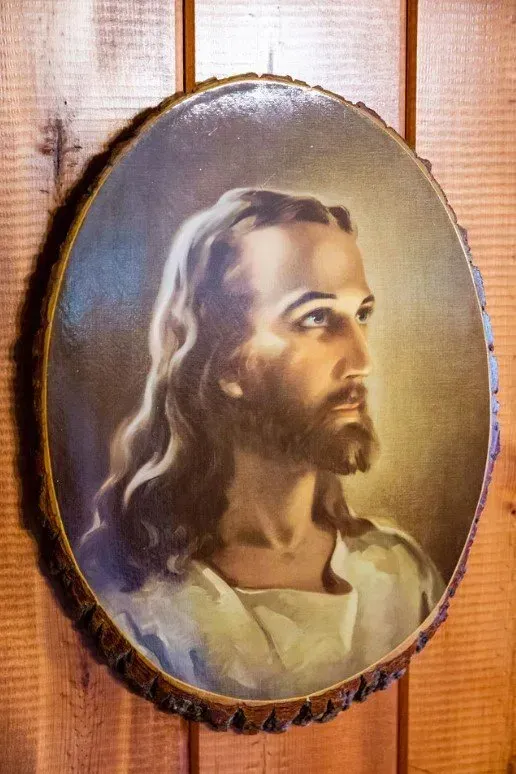 Painting of Jesus on a wooden plaque. He has a beard, looking right.