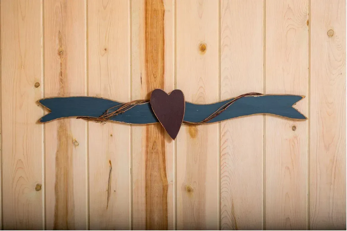 Wooden wall with a dark blue ribbon and brown heart decoration.