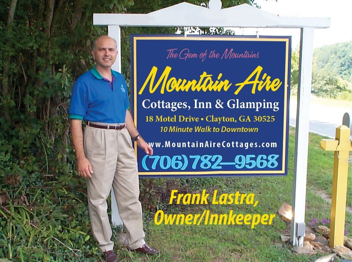 Frank beside the signage of Mountain Aire Cottages, Inn & Glamping.