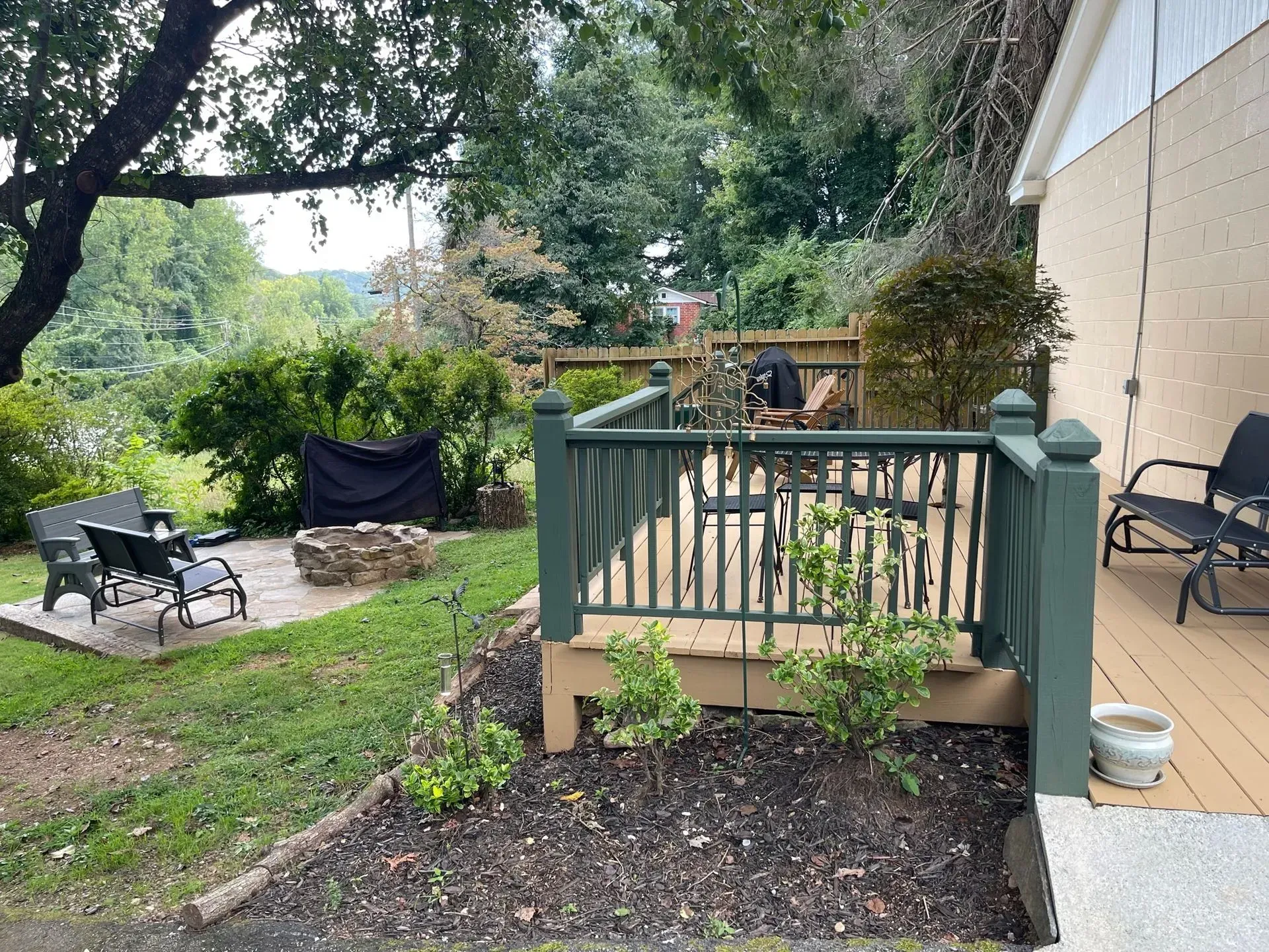 Backyard with a deck, patio, fire pit, and lawn.