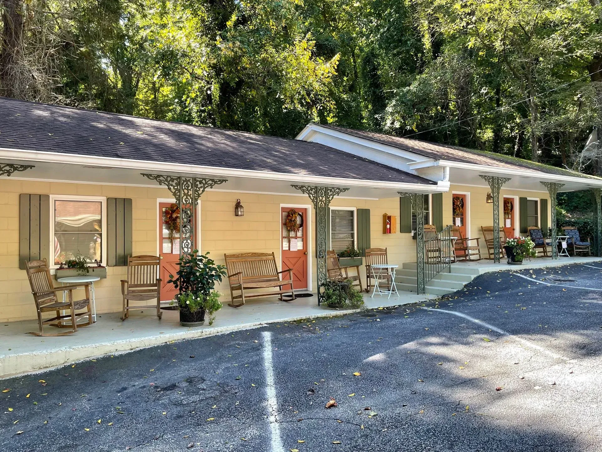 Motel with yellow siding, red doors, porches, and decorative iron supports.
