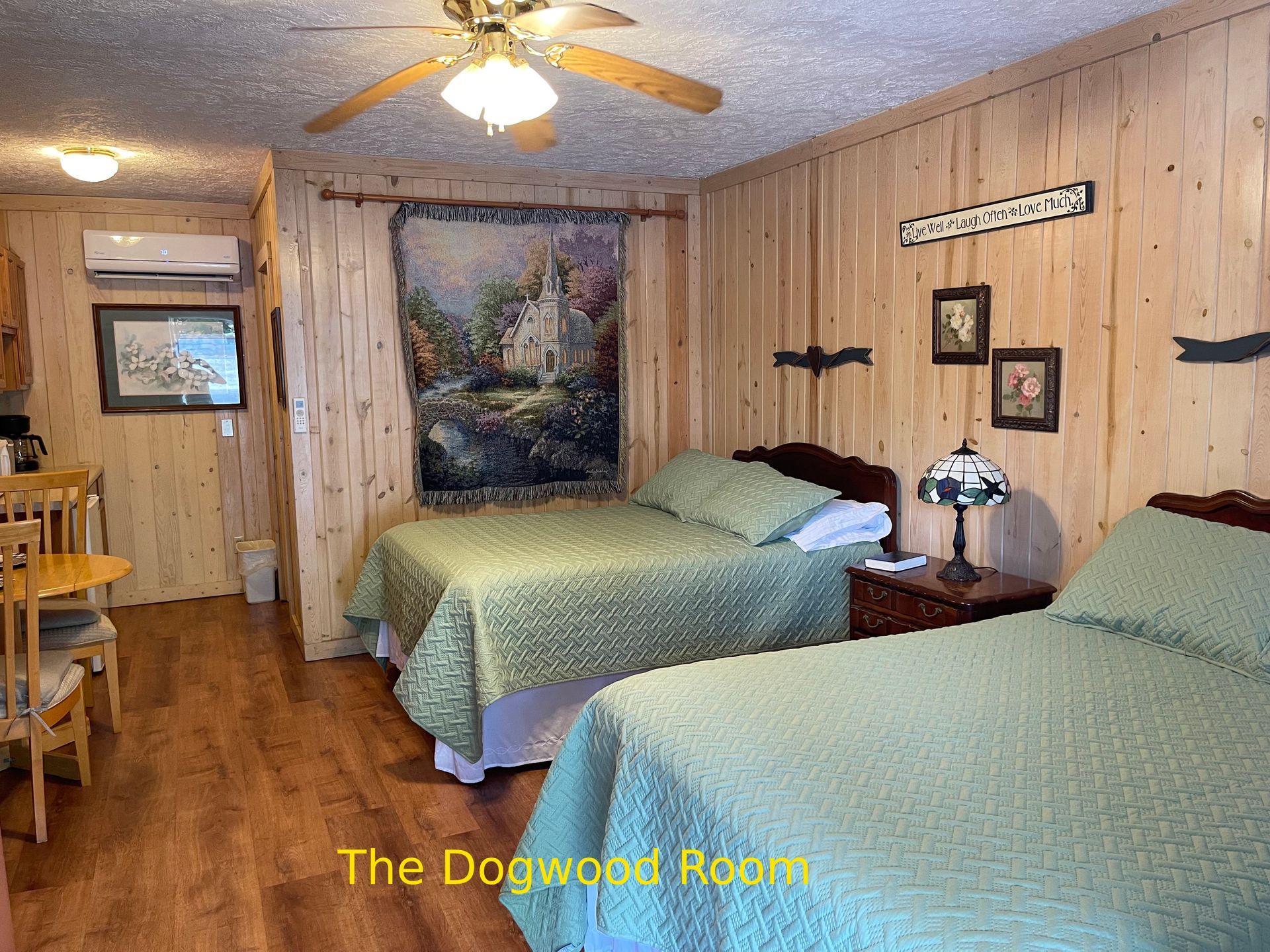 A cozy bedroom with two beds, wood paneling, and a decorative tapestry.