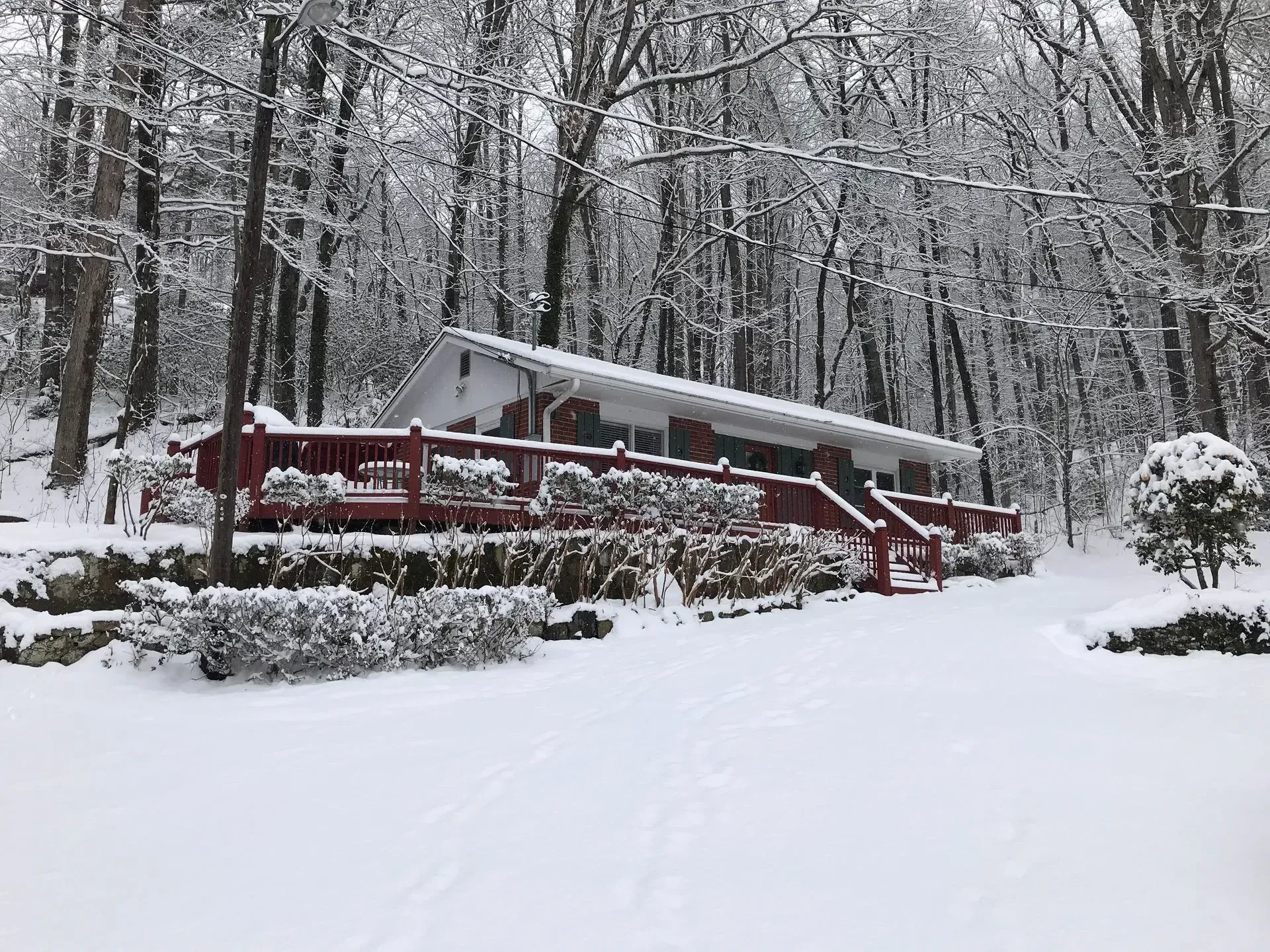 Snowy scene: red-decked cabin nestled among snow-covered trees.
