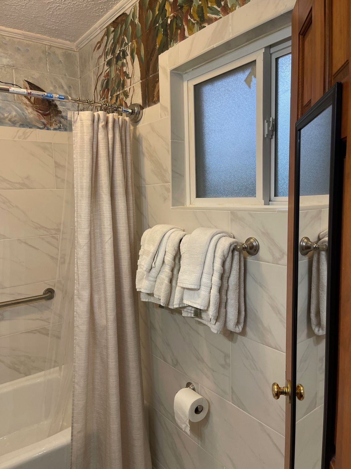 Bathroom with shower, toilet, sink. Gray tiles, white shower curtain. Soap dish, grab bar.