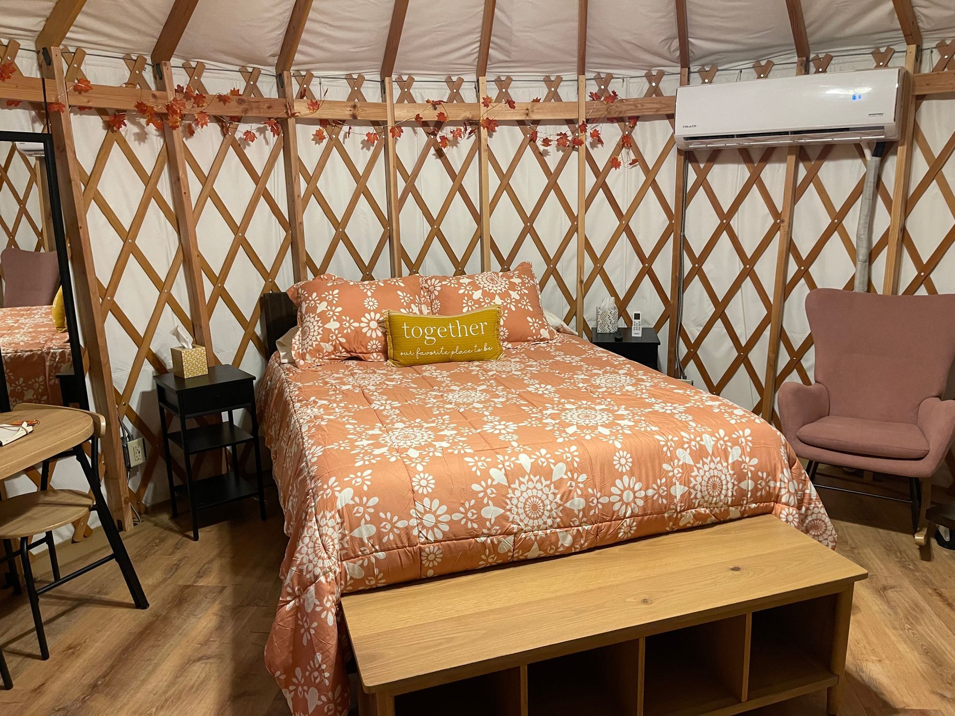 Interior of a yurt with a bed, seating, and a ceiling fan.