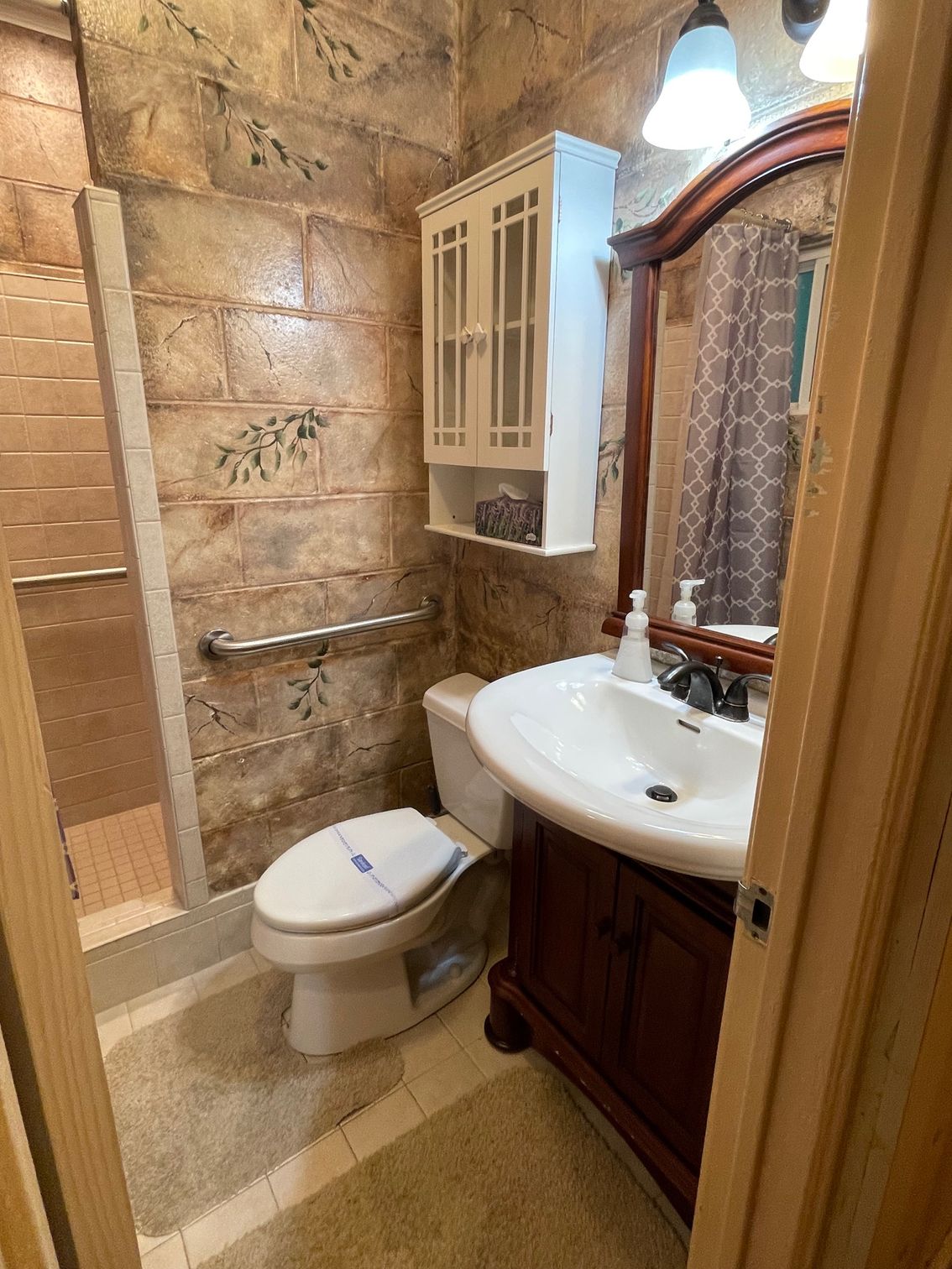 Small bathroom with a white shower curtain, brick-look wall, toilet, and sink.