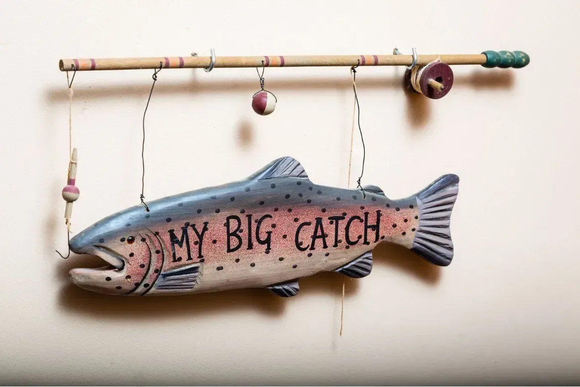 Wooden sign with rainbow trout and fishing pole that reads