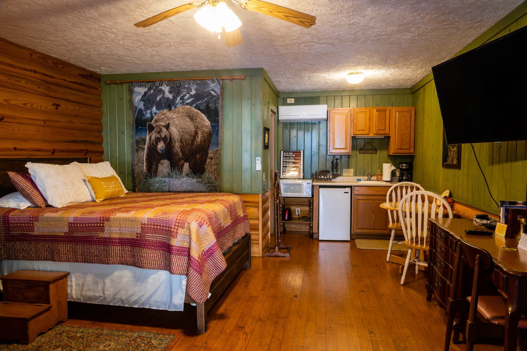 Studio apartment with bed, kitchenette, and bear artwork on the wall.