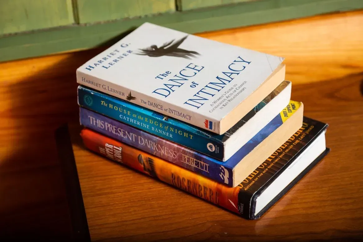 Stack of books on a wooden surface; titles include