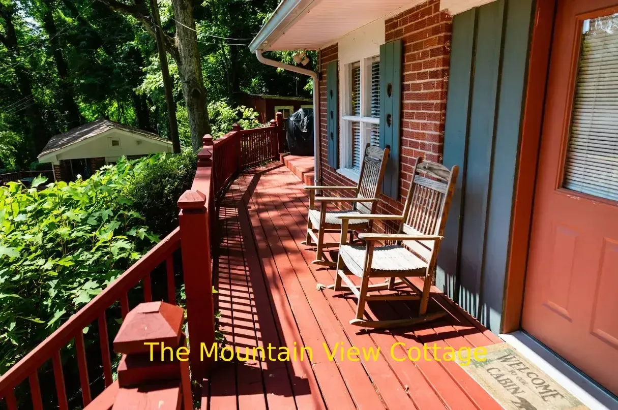 Wooden porch with rocking chairs at The Mountain View Cottage. Red deck, blue shutters, and a red door.