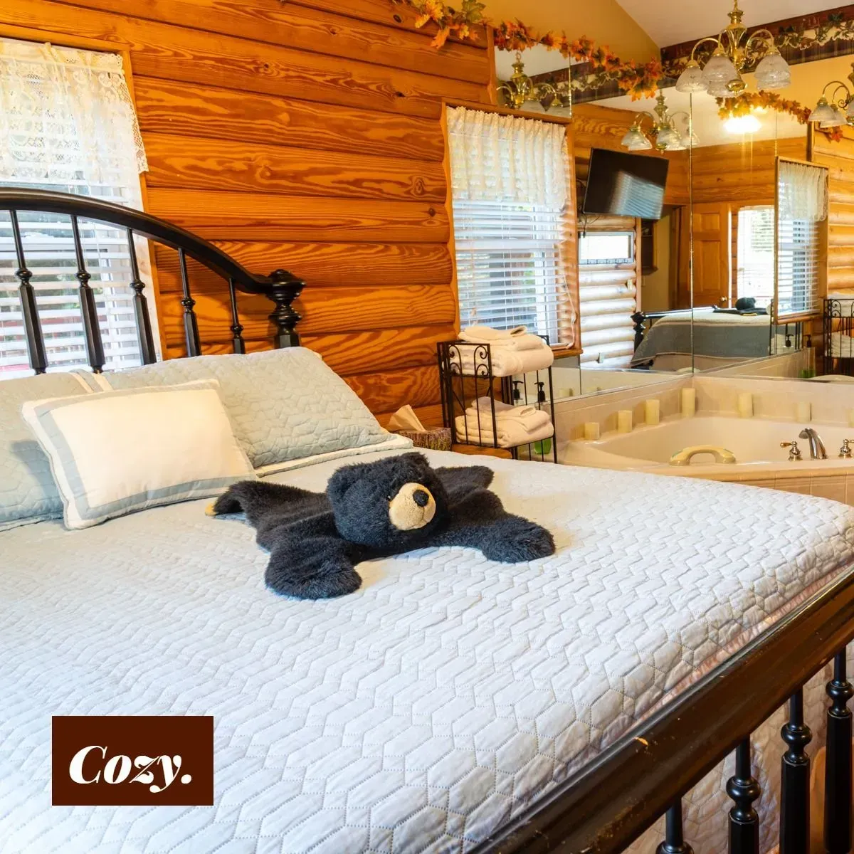 Cozy bedroom with log walls, bed with bear-shaped towel, and jacuzzi.