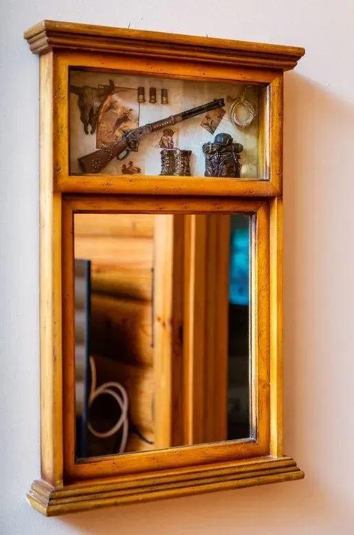 Wooden framed mirror with rifle and hunting accessories.