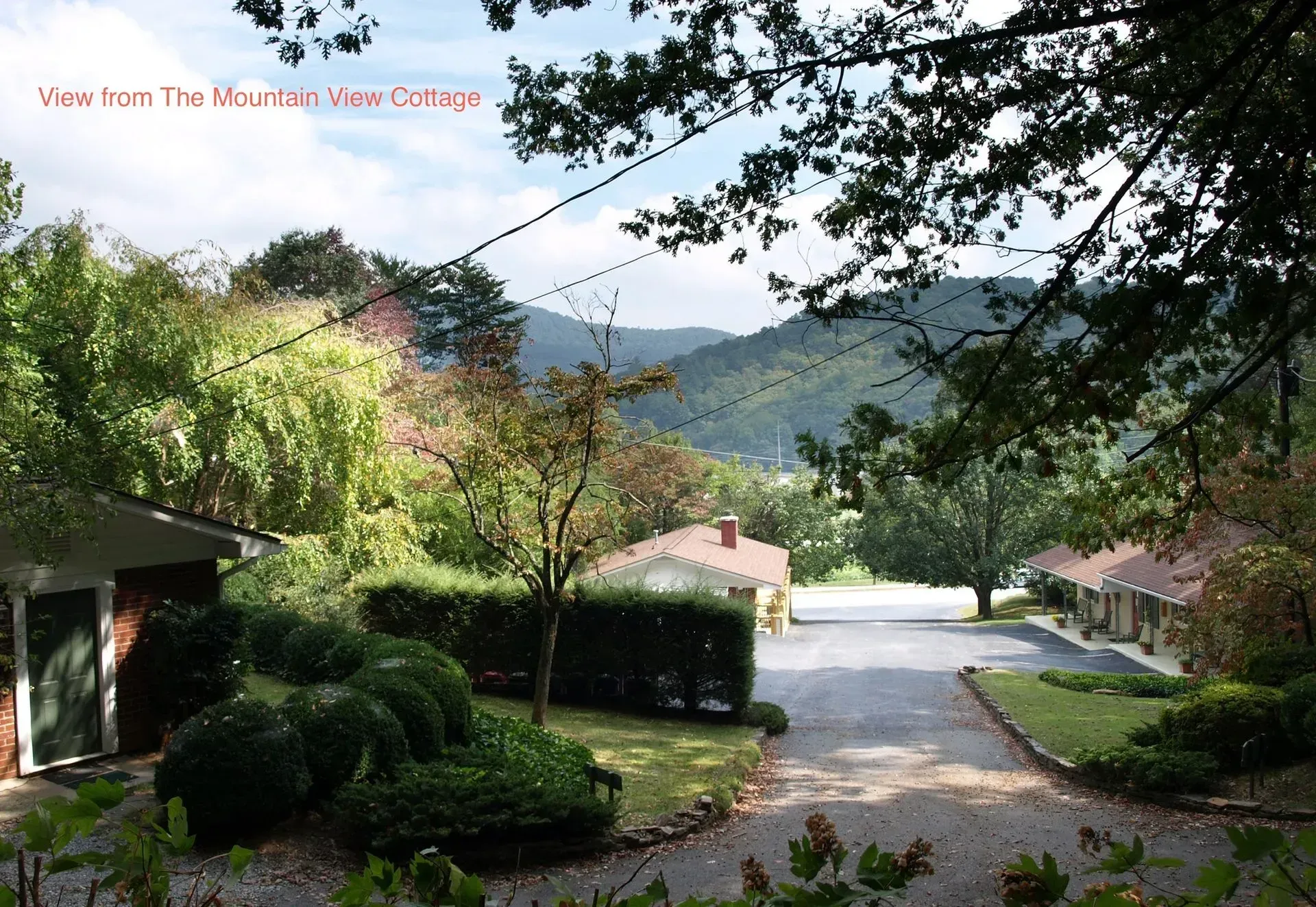 View from Mountain View Cottage: Driveway lined with cottages, lush greenery, mountains in the distance.
