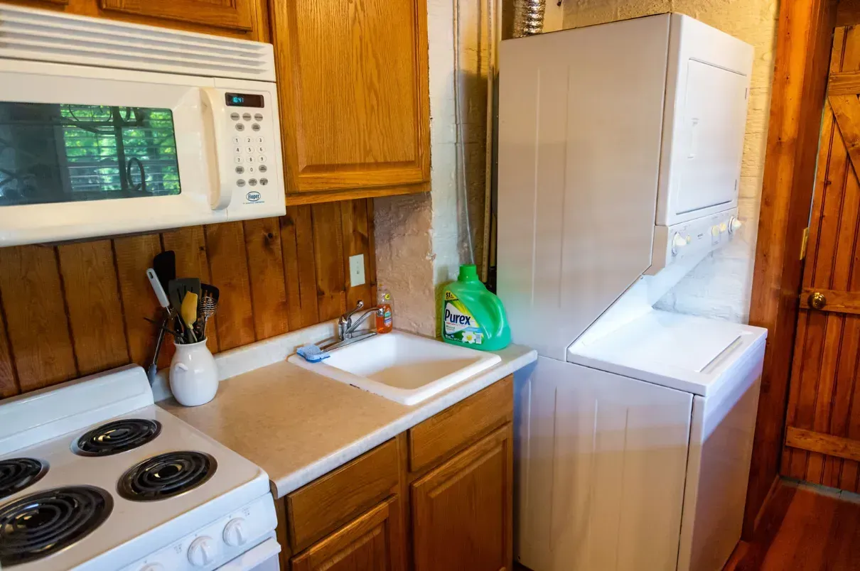Small kitchen with appliances including a stove, microwave, washer and sink.