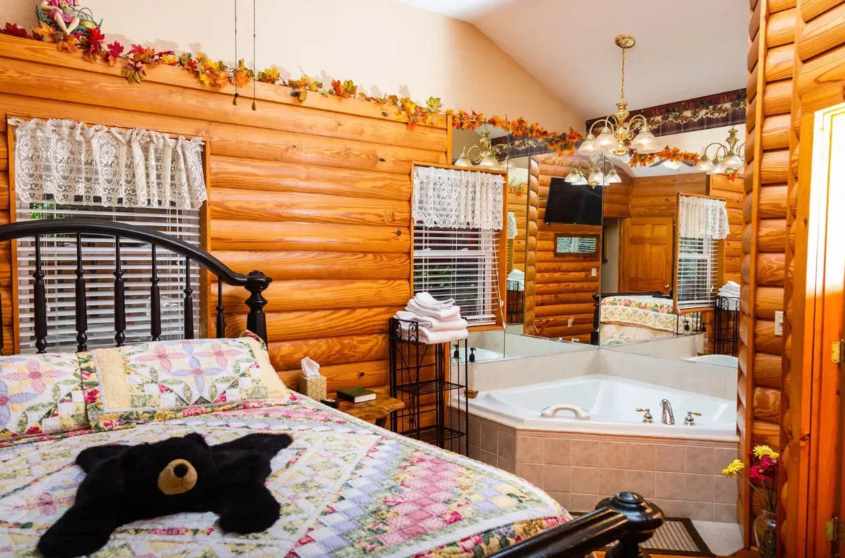 Log cabin bedroom with a bed, a jacuzzi, and a black bear rug.