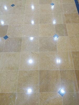 Tan square floor tiles with blue diamond insets reflect bright light.
