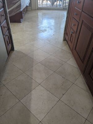 Beige tile kitchen floor with brown cabinets on either side.