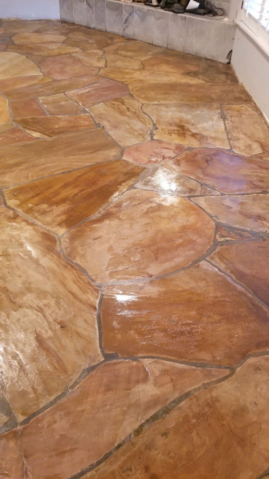 Brown and tan flagstone flooring, shiny and reflective.