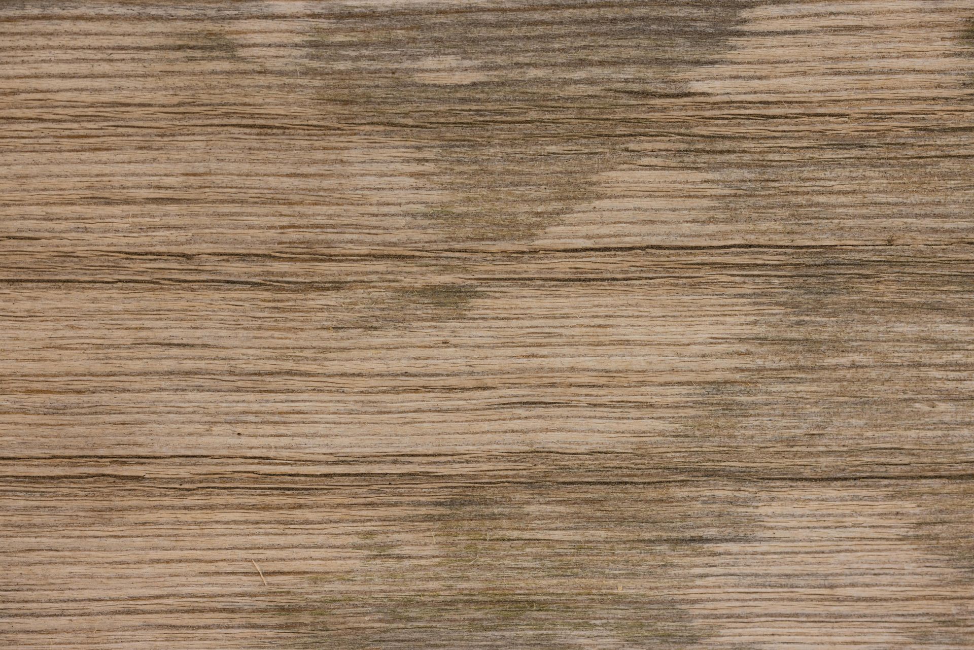 Close-up of weathered wooden planks with horizontal grain and faded gray-brown color.